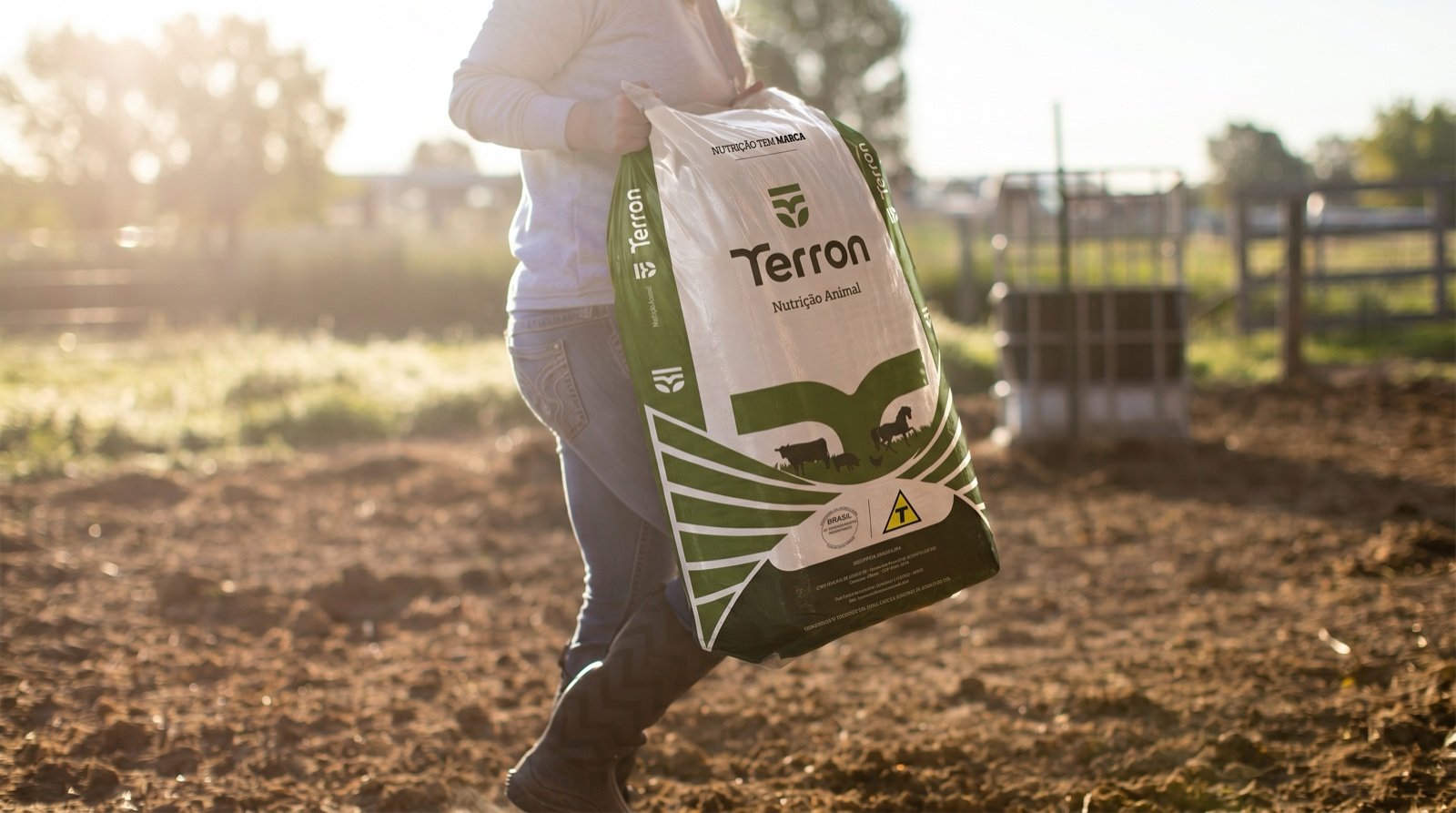 Produtor carrega uma sacaria da Terron pelo pasto, ao amanhecer
